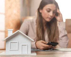 joven mujer junto a casa de madera aprendiendo cómo evitar fraudes con créditos hipotecarios.