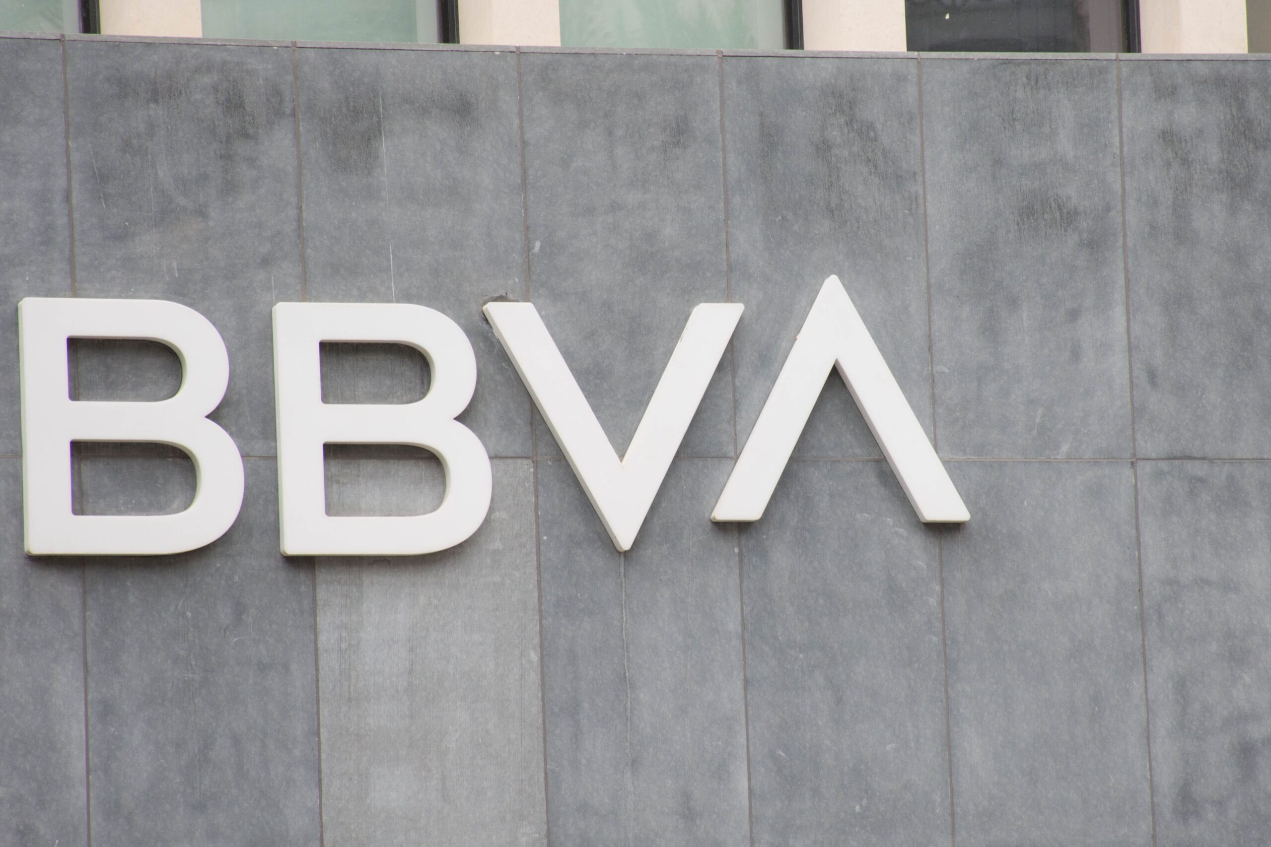 Logo en blanco de BBVA sobre un muro gris