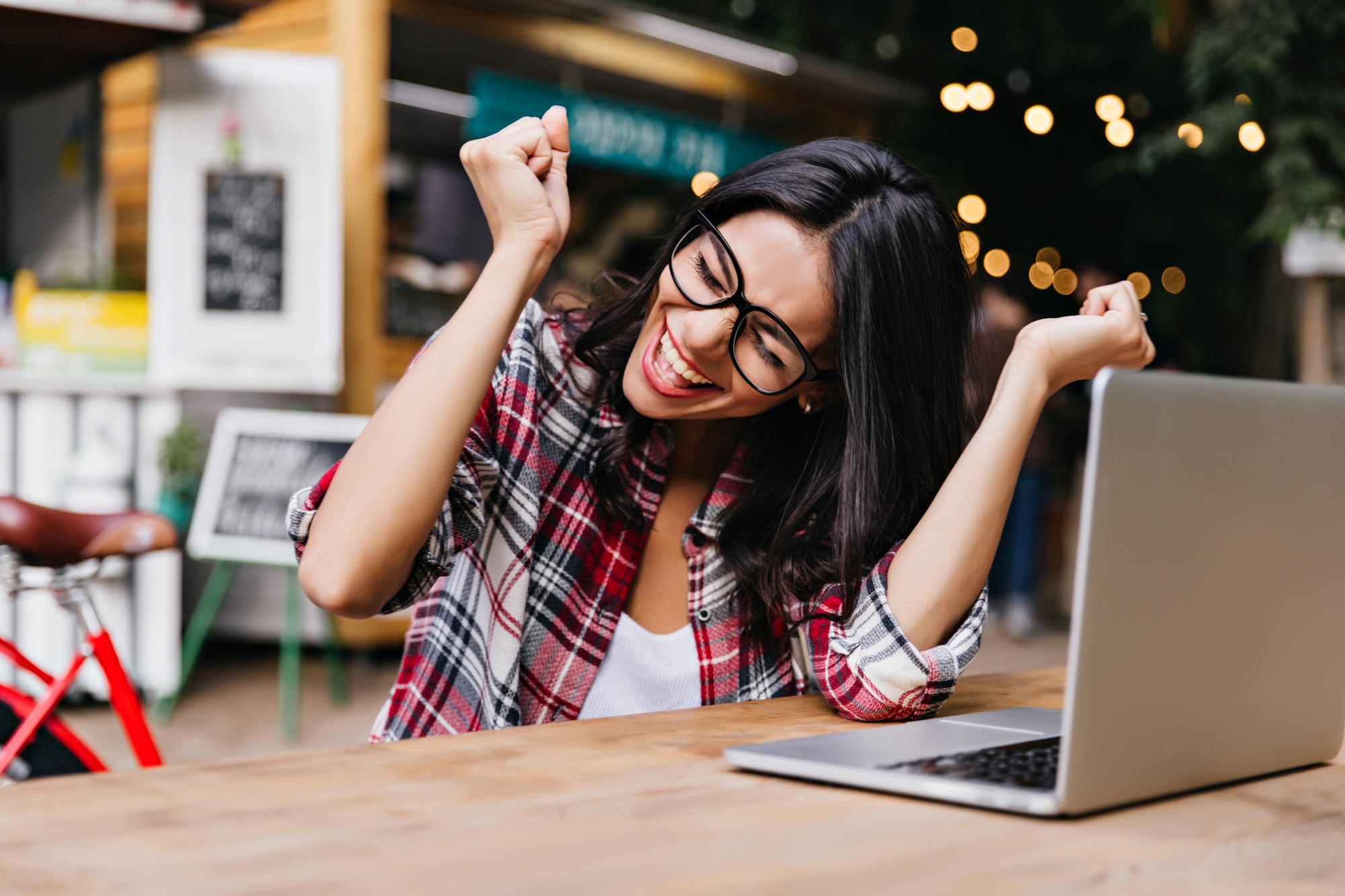 Mujer sentada frente a una computadora celebrando por aprovechar sus puntos en el programa Scotia Rewards.