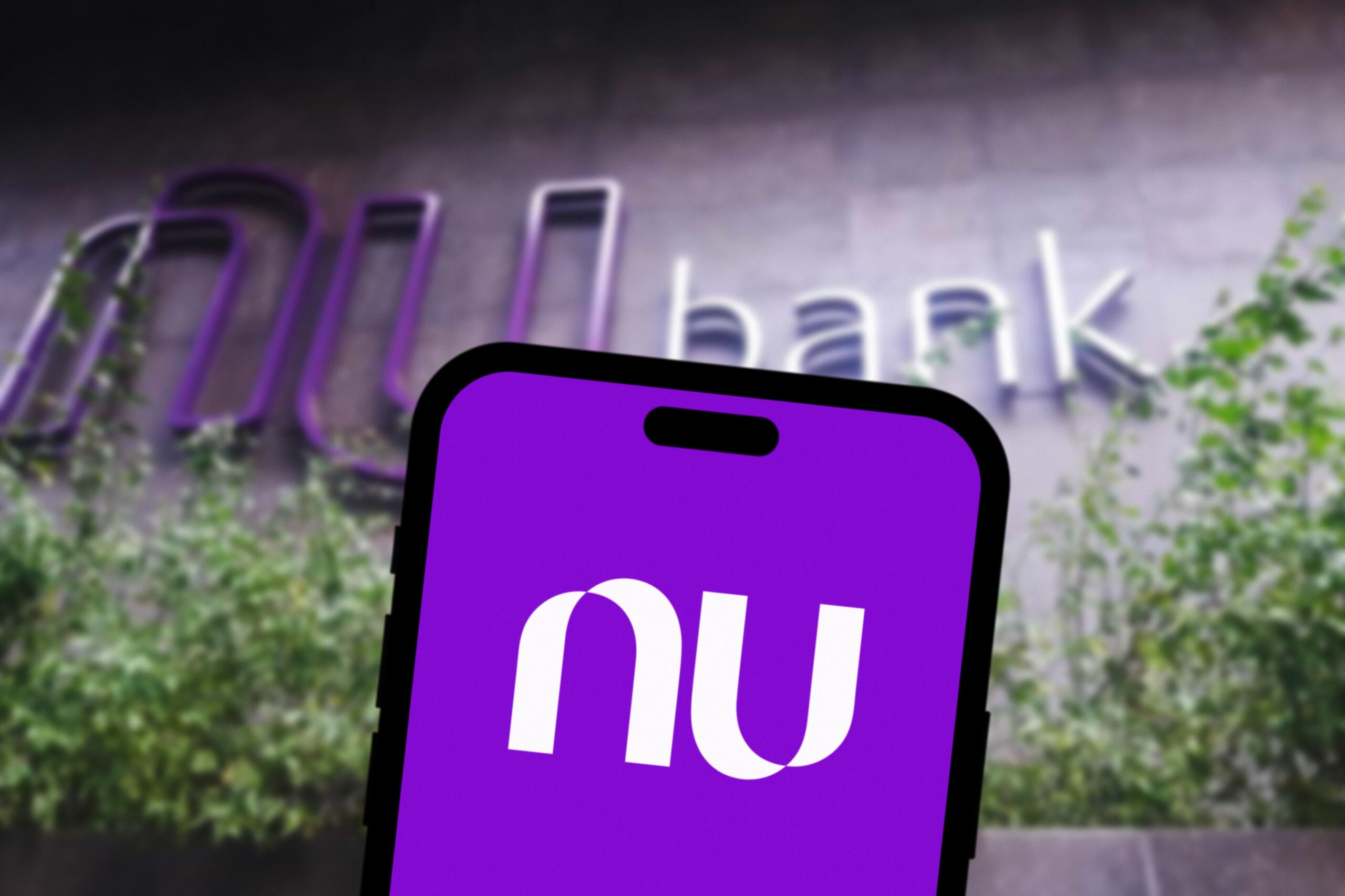 Celular con aplicación de Nubank enfrente de una de las oficinas de esta empresa.