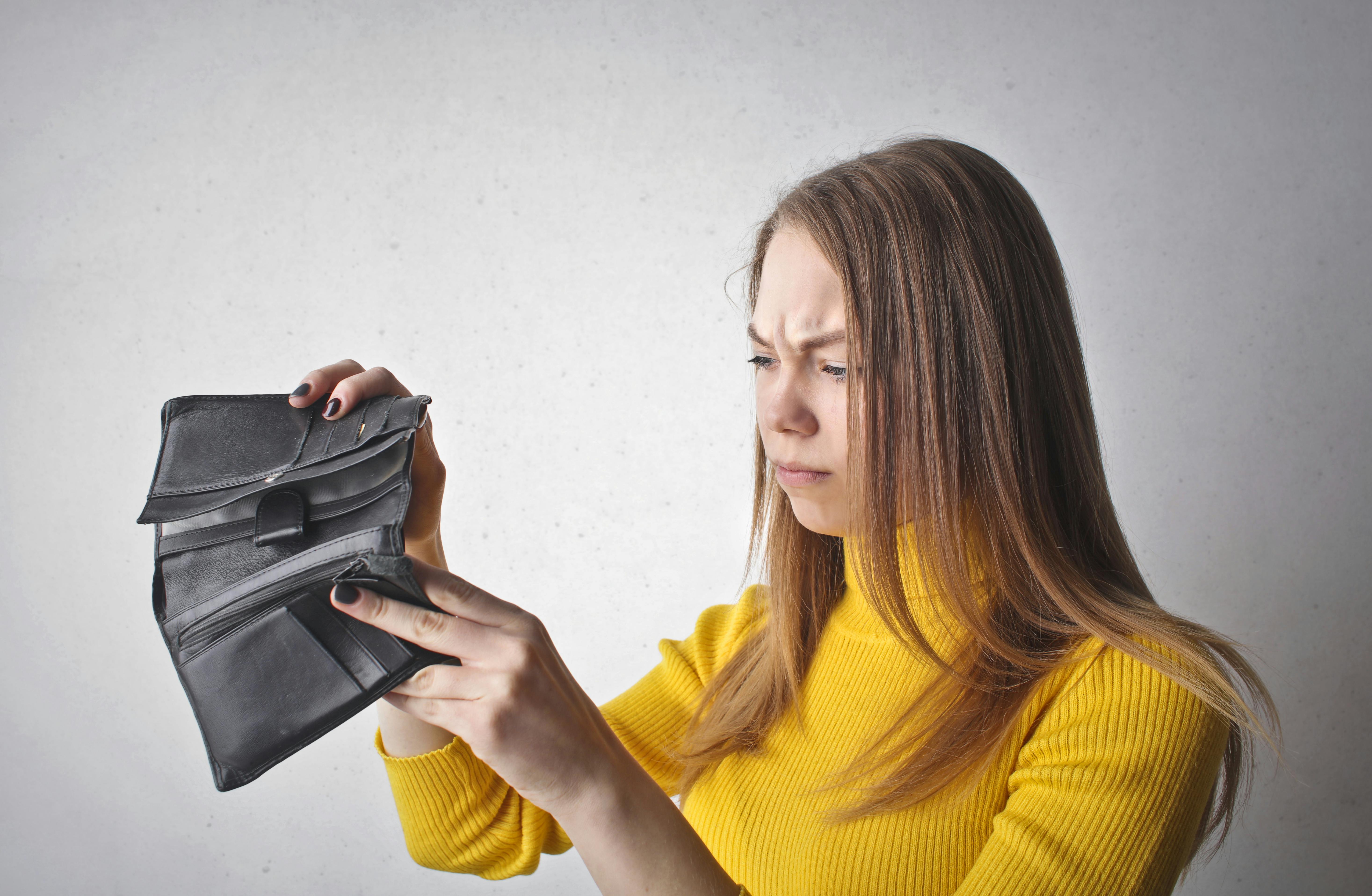 Mujer revisando su falta de dinero en la cartera durante el día mundial del ahorro