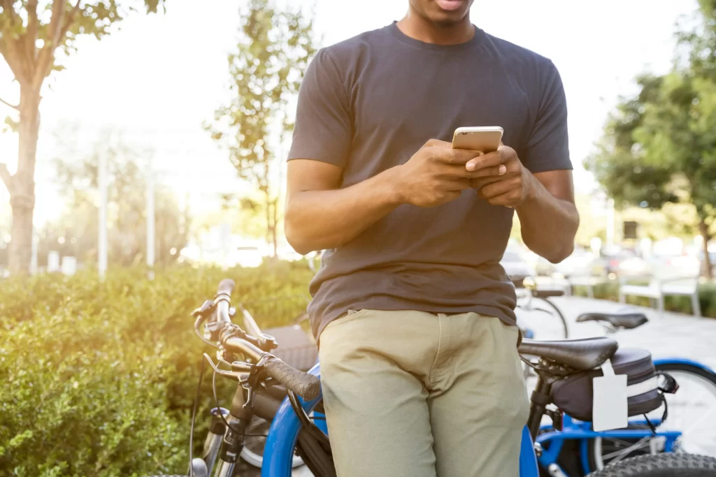 Hombre joven usando su celular en la vía pública, donde podría estar en riesgo de no contar con un seguro de gadgets.