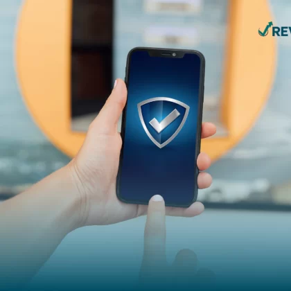 Persona sosteniendo un celular mostrando un escudo en la pantalla que