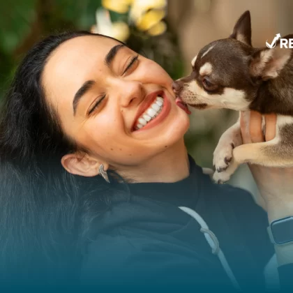 Mujer cargando a su perro mientras la lame después de investigar las aseguradoras para mascotas que lo protegen de accidentes y enfermedades.