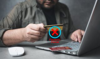 Hombre sentado frente a una computadora intentando hacer un pago con una tarjeta Nanopay