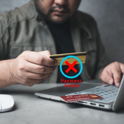 Hombre sentado frente a una computadora intentando hacer un pago con una tarjeta Nanopay