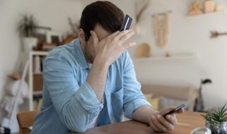 Hombre preocupado por no saber qué pasa si no puede pagar su tarjeta de crédito