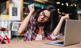 Mujer sentada frente a una computadora celebrando por aprovechar sus puntos en el programa Scotia Rewards.
