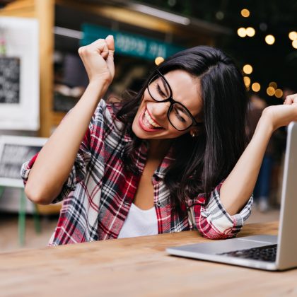Mujer sentada frente a una computadora celebrando por aprovechar sus puntos en el programa Scotia Rewards.