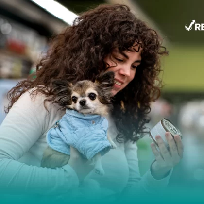 Mujer cargando a su perro mientras hace las compras y piensa cuál es el mejor seguro para perros.
