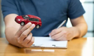 Hombre sosteniendo un auto de juguete mientras contrata un seguro de auto Scotiabank.